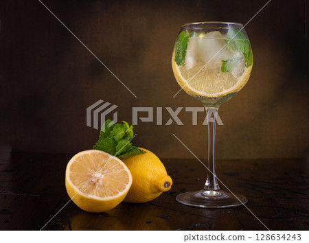 Refreshing summer drink in a glass. Cocktail. Lemon and mint in a glass. Vintage still life. Refreshing summer drink in a glass. Cocktail. Lemon and mint in a glass. Vintage still life. 128634243