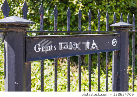 Accessible Gents Toilet sign on wrought iron fence in public park, London UK Accessible Gents Toilet sign on wrought iron fence in public park, London UK 128634709