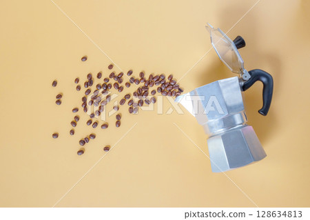 top view of aluminium moka pot and scattered fresh coffee beans. top view of aluminium moka pot and scattered fresh coffee beans. 128634813