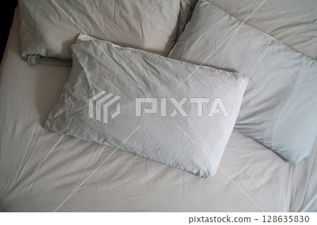Pillows with fresh clean pillowcases, grey cotton bed sheets Pillows with fresh clean pillowcases, grey cotton bed sheets 128635830