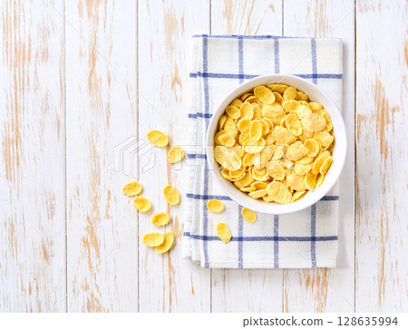 ceramic bowl of tasty corn flakes on a light kitchen table, Top view. Copy space for text. 128635994