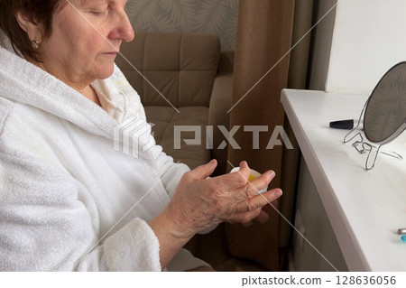 A charming senior woman is at her house, beautifying herself for the morning. 128636056