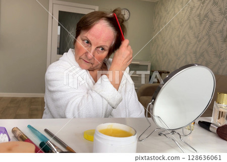 A sophisticated senior woman is at home, focusing on her morning grooming. 128636061