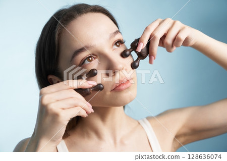 Woman applying facial roller for skincare routine in bright indoor space Woman applying facial roller for skincare routine in bright indoor space 128636074