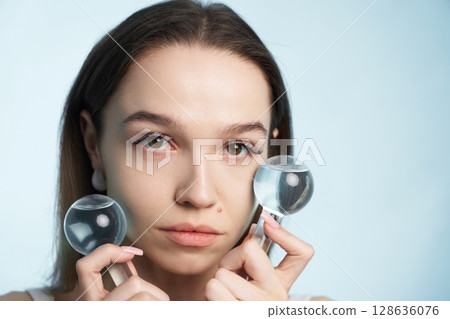 Woman using magnifying glasses for skin analysis in a studio setting 128636076