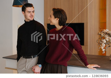 Couple enjoying time together in cozy sweaters at modern kitchen 128636093