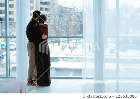 Couple enjoying a snowy city view from a cozy indoor setting Couple enjoying a snowy city view from a cozy indoor setting 128636096