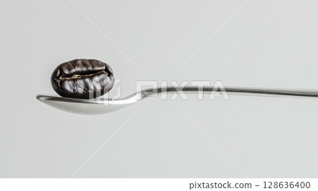 Minimalist macro shot of coffee bean on silver spoon 128636400