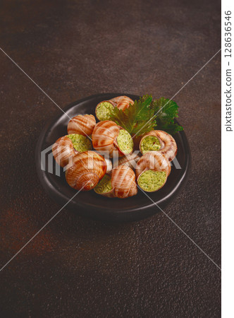 snails stuffed in Burgundy, on a black plate, with grape leaves, French cuisine, no people, 128636546