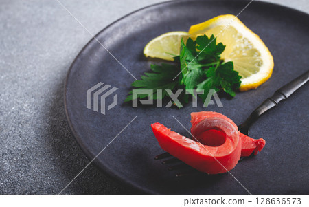 chum salmon, cold smoked, on a fork, with lemon and parsley, top view, close-up, no people, 128636573