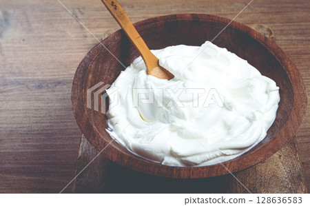 sour cream in a wooden bowl, on a wooden table, top view, close-up, no people, 128636583