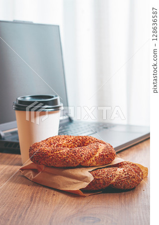 simits with coffee on a wooden table, with a laptop, in a cozy working environment, snack, breakfast, no people, simits with coffee on a wooden table, with a laptop, in a cozy working environment, snack, breakfast, no people, 128636587