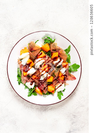 salad with slices of ripe melon, prosciutto, mozzarella and fresh arugula, decorated with balsamic glaze. salad with slices of ripe melon, prosciutto, mozzarella and fresh arugula, decorated with balsamic glaze. 128636605