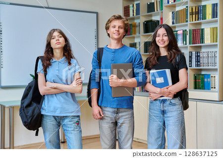 Portrait of three teenage students, smiling teenagers guy and girls looking at camera in classroom Portrait of three teenage students, smiling teenagers guy and girls looking at camera in classroom 128637125