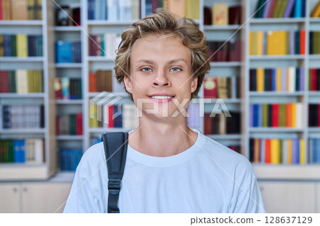 Headshot portrait of handsome smiling teenage boy looking at camera in library Headshot portrait of handsome smiling teenage boy looking at camera in library 128637129