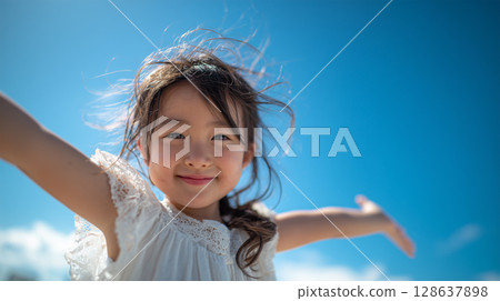 一位日本小女孩在藍天下張開雙臂 一位日本小女孩在藍天下張開雙臂 128637898