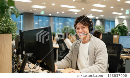 Smiling young operator with dual screen capabilities 128637906