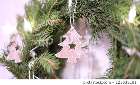 A close-up view of a festive Christmas wreath, adorned with charming wooden Christmas tree ornaments. 128639191
