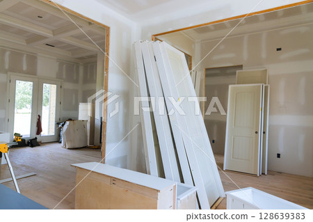 Stacked white doors unfinished walls indicate ongoing renovation work in an expansive home interior. 128639383
