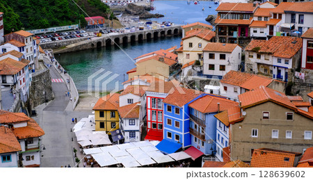 A picturesque view of a charming coastal village nestled into a hillside, with colorful traditional houses cascading down towards a tranquil harbor. Cudillero, Spain 128639602