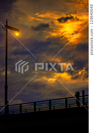 一位女士站在橋上拍攝路燈 128640048