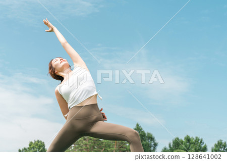 Young Asian woman doing park yoga, yoga, pilates, stretching in forest/park 128641002