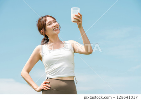 婦女在運動時飲用蛋白質/EAA 飲料(藍天) 婦女在運動時飲用蛋白質/EAA 飲料(藍天) 128641017