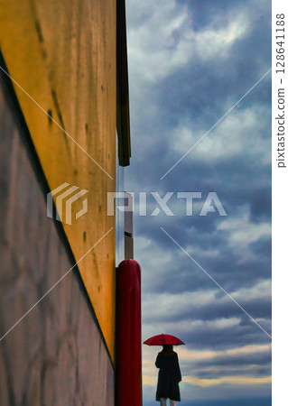 Woman with red umbrella and black coat 128641188