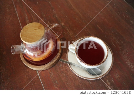 An Elegant Tea Presentation Featuring a Pot and Cup Tastefully Arranged on a Wooden Table 128641638