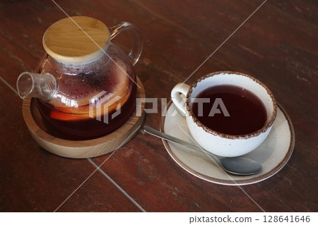 A cozy teapot of warm herbal tea rests on a smooth wooden surface, inviting comfort 128641646
