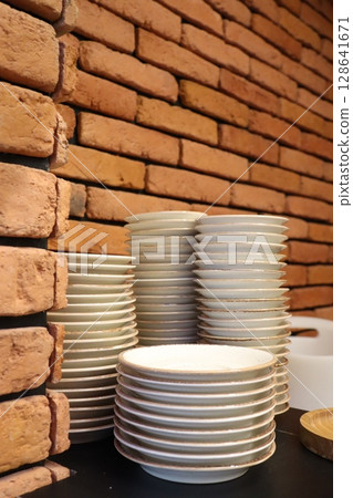 A stunning display of stacked plates placed gracefully against a rustic brick wall background, A stunning display of stacked plates placed gracefully against a rustic brick wall background, 128641671