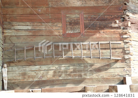 A Rustic Wall with an Elegant Ladder and a Beautiful Wooden Figure Nearby, Evoking Nostalgia A Rustic Wall with an Elegant Ladder and a Beautiful Wooden Figure Nearby, Evoking Nostalgia 128641831