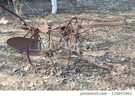 A Rusty Antique Plow Set Against the Backdrop of Beautiful Nature and Scenic Landscapes A Rusty Antique Plow Set Against the Backdrop of Beautiful Nature and Scenic Landscapes 128641862