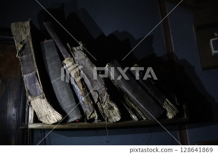 A Stunning Collection of Weathered and Antique Books Artfully Displayed upon a Dark Shelf 128641869