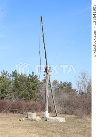 A Tall Rustic Wooden Pole Stands Proudly Against a Bright Blue Sky, Enhancing Countryside Beauty 128641909
