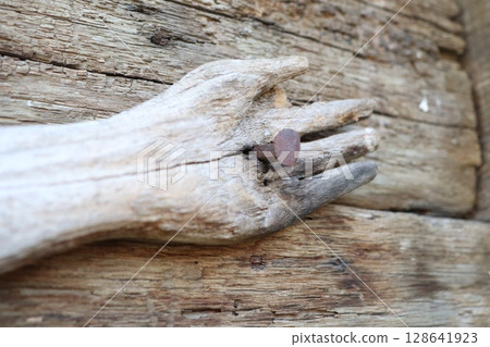 Artistic wooden hand displaying nails against a rustic wood background, evoking nature Artistic wooden hand displaying nails against a rustic wood background, evoking nature 128641923