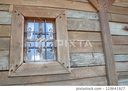 A Rustic Window adorned with Decorative Iron Bars set against a Wood Wall background panel 128641927