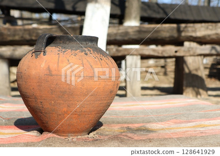 A Rustic Clay Pot Beautifully Displayed on a Wooden Table, Surrounded by a Charming Atmosphere 128641929