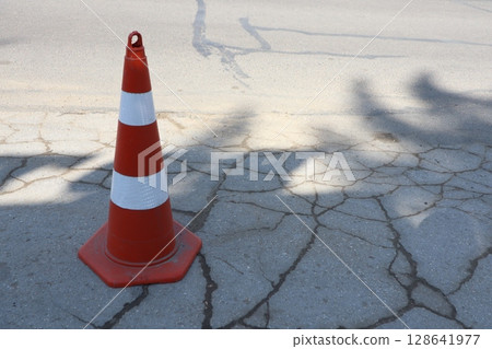 A traffic cone placed on a cracked pavement section captures attention and enhances safety 128641977