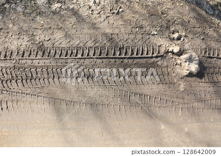 Tire Tracks Present on a Dirt Surface Illuminated by Natural Light During the Daytime Tire Tracks Present on a Dirt Surface Illuminated by Natural Light During the Daytime 128642009
