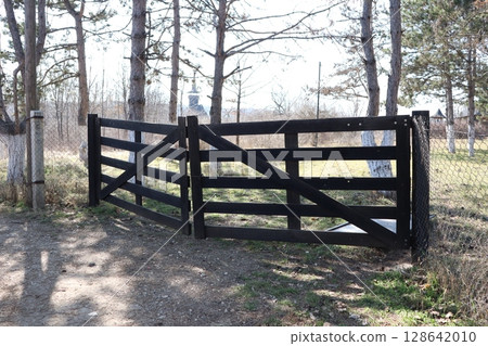 A Beautifully Designed Elegant Black Wooden Gate Surrounded by Lush Nature and Landscape A Beautifully Designed Elegant Black Wooden Gate Surrounded by Lush Nature and Landscape 128642010