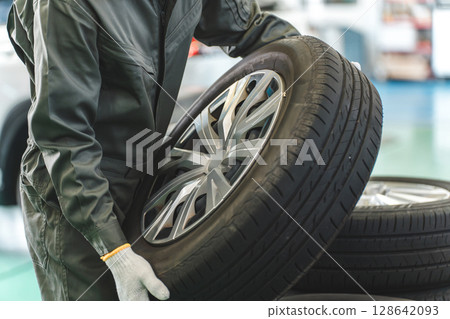在汽車修理廠運輸輪胎的男性機械師(體力勞動、苦力勞動、繁重工作、背痛) 在汽車修理廠運輸輪胎的男性機械師(體力勞動、苦力勞動、繁重工作、背痛) 128642093