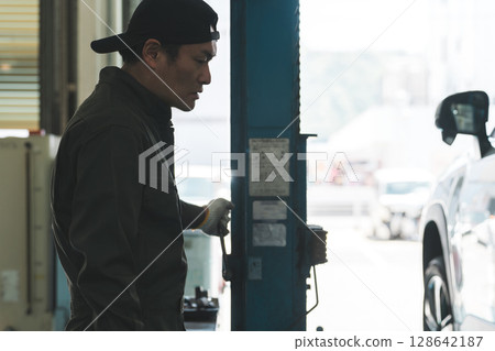 A male mechanic operating a lift at a maintenance workshop A male mechanic operating a lift at a maintenance workshop 128642187
