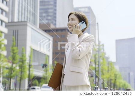 一位年輕女商人在辦公區用智慧型手機交談的畫像 一位年輕女商人在辦公區用智慧型手機交談的畫像 128642455