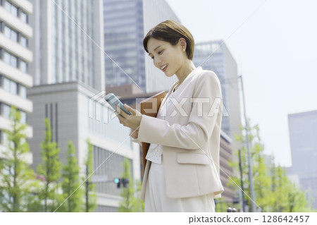 一位年輕女商人在辦公區操作智慧型手機的畫像 一位年輕女商人在辦公區操作智慧型手機的畫像 128642457