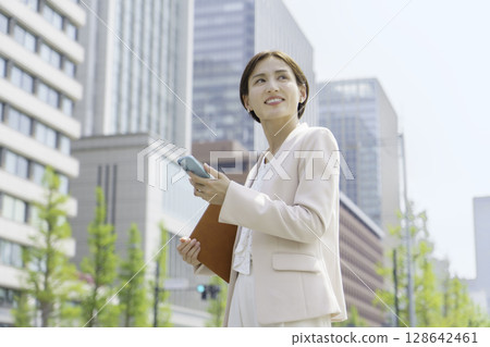 一位年輕女商人在辦公區操作智慧型手機的畫像 128642461