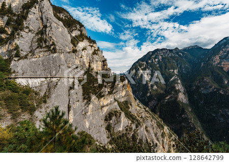 Sunlit mountain walkway overlooking deep gorge in Balagezong, Shangri-La, China 128642799
