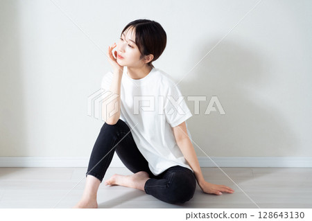 Portrait of a young woman sitting on the floor Portrait of a young woman sitting on the floor 128643130