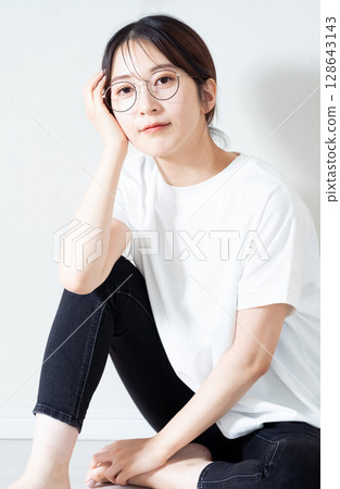 Portrait of a young woman sitting on the floor 128643143