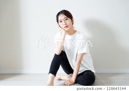 Portrait of a young woman sitting on the floor Portrait of a young woman sitting on the floor 128643144